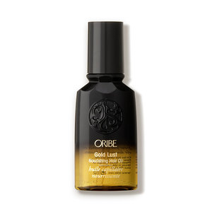 Oribe Gold Lust Nourishing Hair Oil in a sleek black and gold bottle, featuring a textured emblem and clear labeling, travel size 50ml/1.7oz.