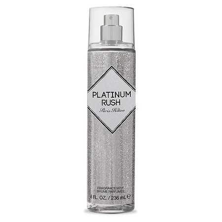 Clear spray bottle filled with shimmering silver body mist, featuring a diamond-shaped label that reads "PLATINUM RUSH" and "Paris Hilton" in elegant fonts.