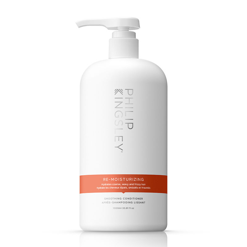 White plastic bottle with a pump dispenser, labeled "Re-Moisturizing Smoothing Conditioner" in black and orange text, 33.8 fl oz size, by Philip Kingsley.