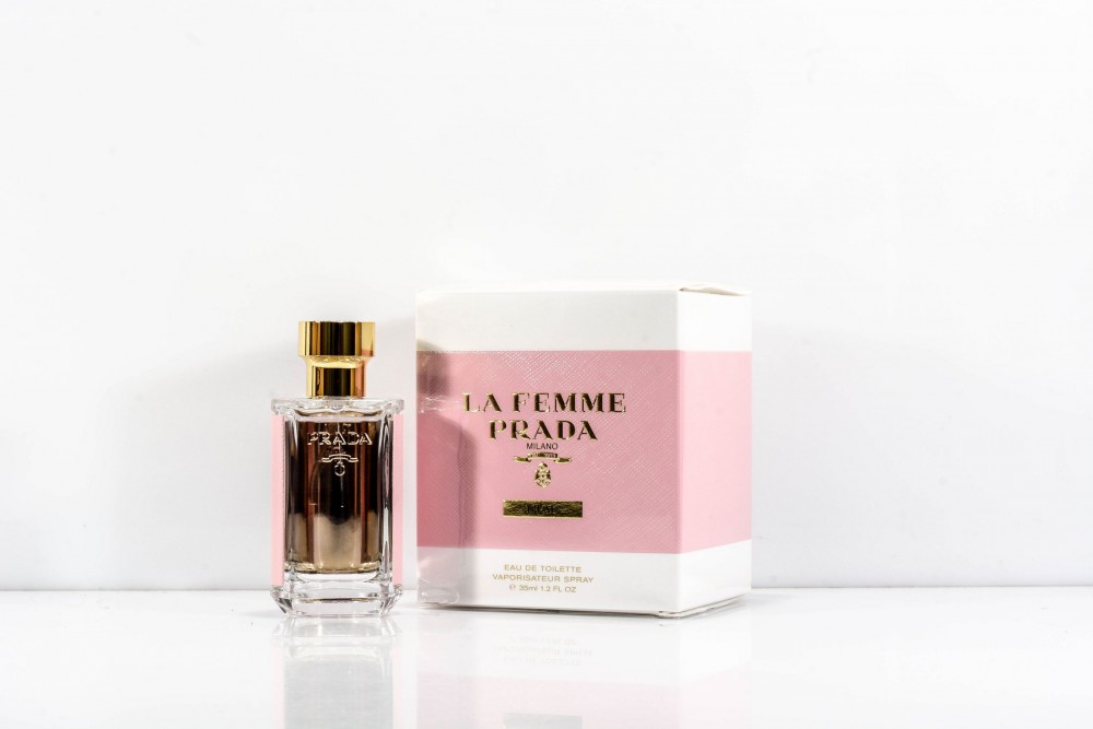 Prada La Femme L'Eau Eau De Toilette 35ml spray features a clear glass bottle with a gold cap and a pink and white box adorned with elegant text.