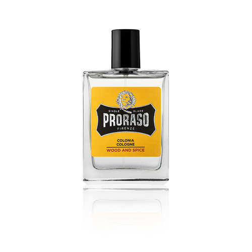 Clear glass cologne bottle with a black cap, featuring a bold yellow label that reads "Proraso Colonia Wood and Spice" in black and white text.