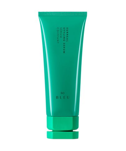 Bright teal tube of R+Co Bleu Surreal Styling Serum, 148ml, featuring a sleek design with white text and a matching green cap.
