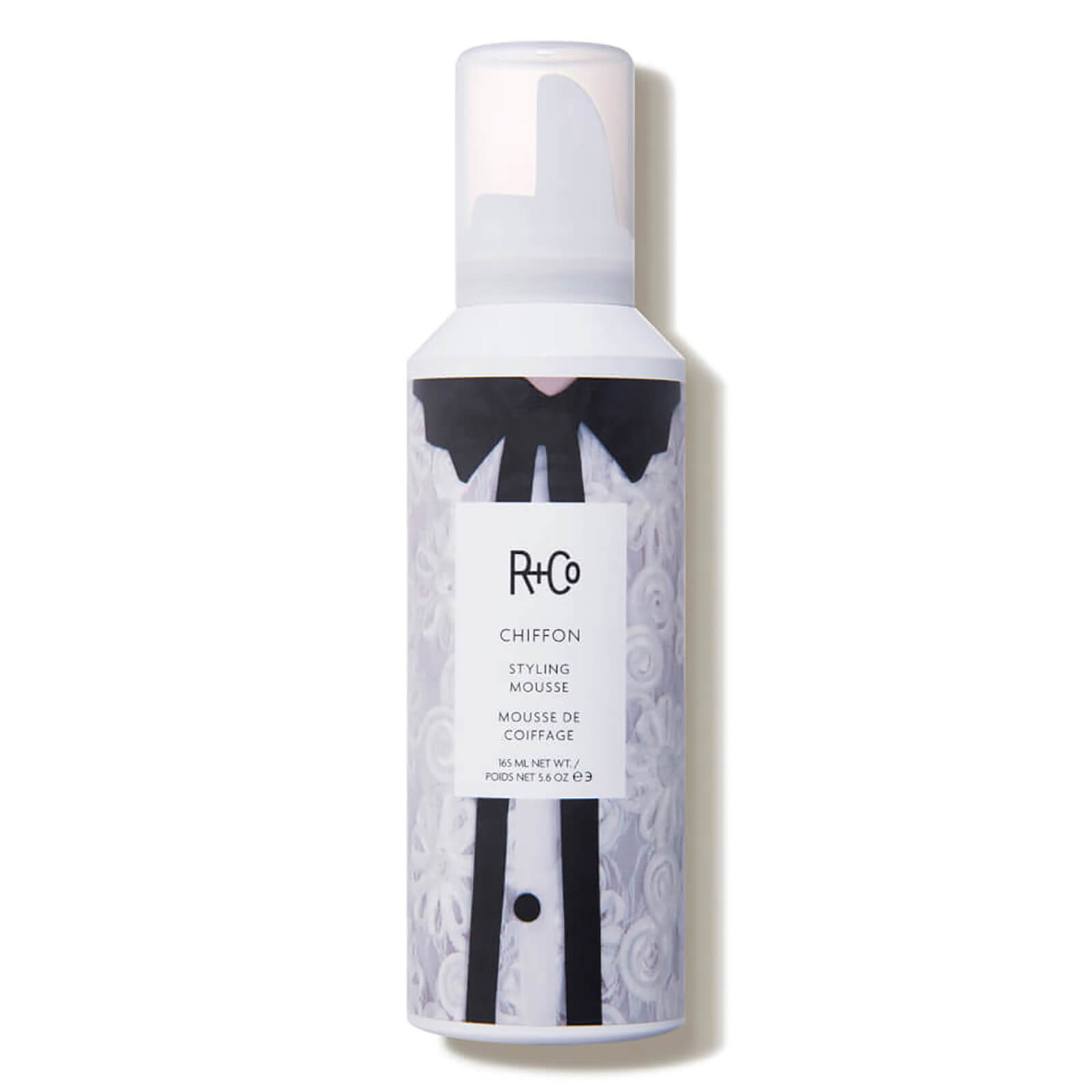 White aerosol can featuring a stylish design with a black and white illustration, labeled "R+Co Chiffon Styling Mousse," 165 ml, with a pump dispenser on top.