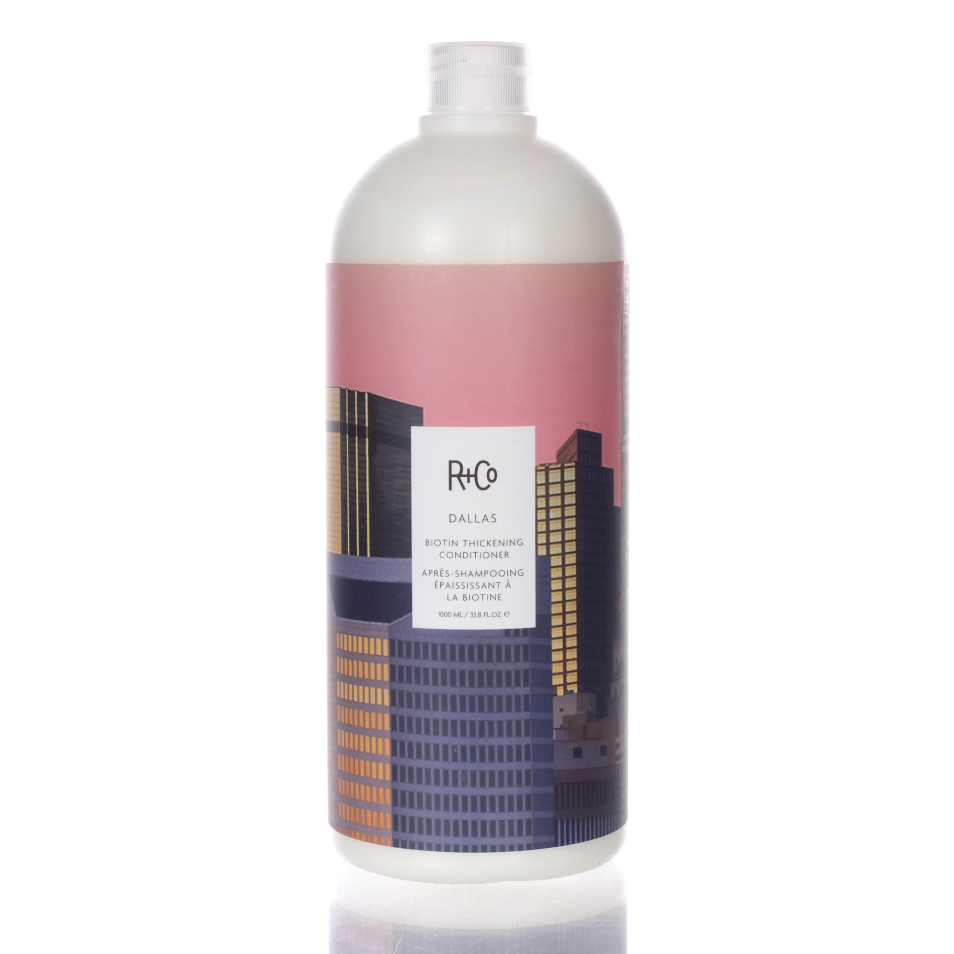 R+Co DALLAS THICKENING CONDITIONER in a 33.8 oz bottle features a pink and dark blue label with city skyline graphics, designed for unisex use.