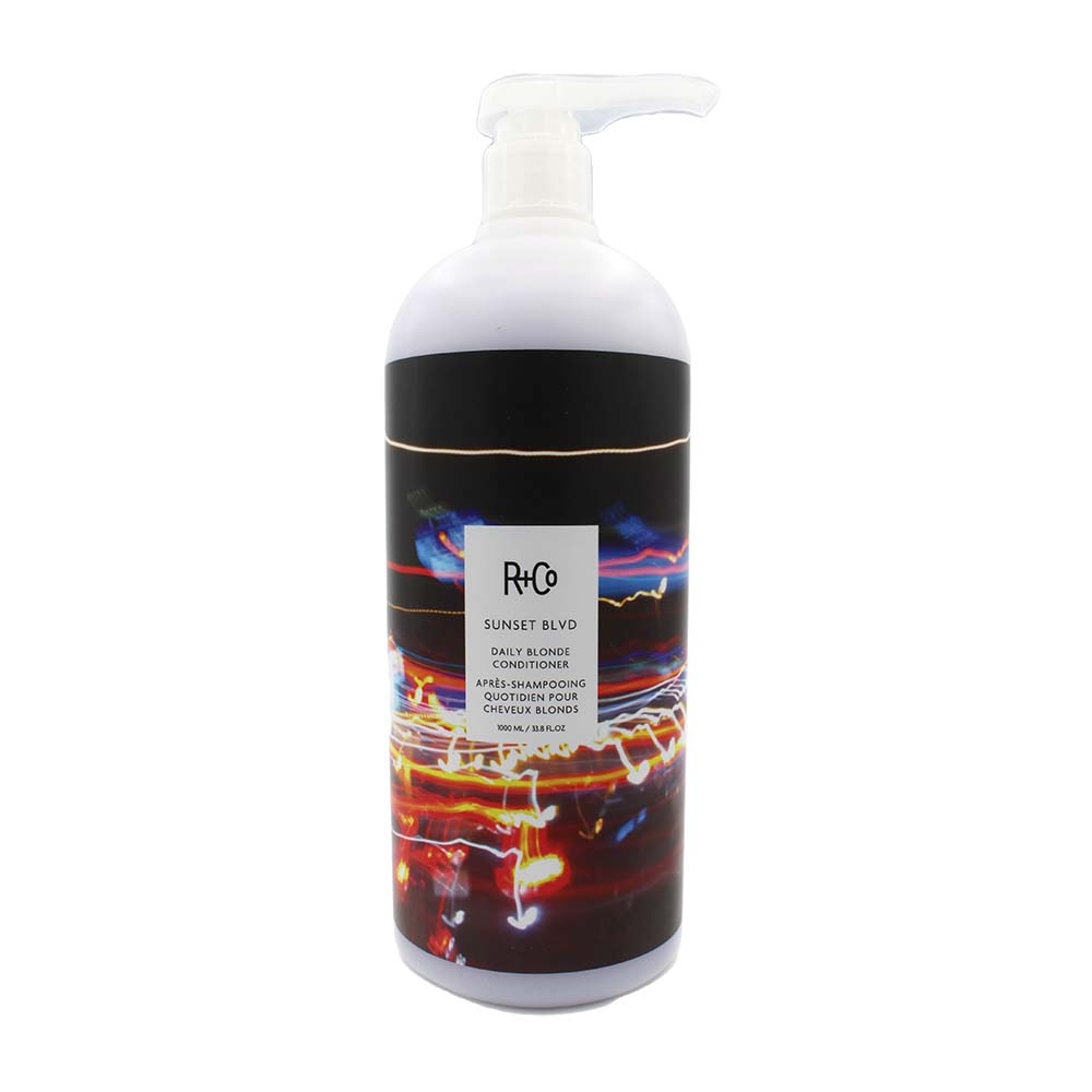 White bottle with a pump top, featuring a vibrant, abstract design of colorful lights, labeled "R+Co SUNSET BLVD Daily Blonde Conditioner 1000ml/33.8oz."