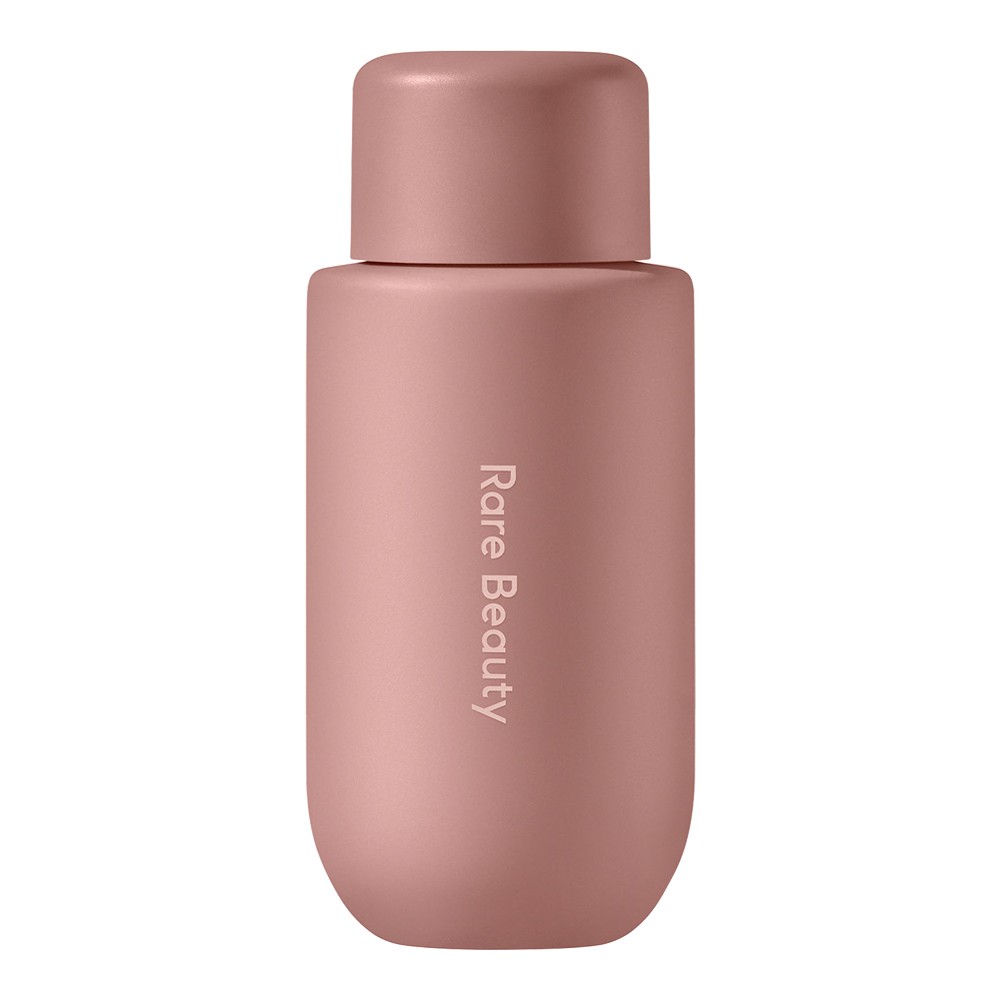 Light pink, matte bottle of Rare Beauty's Mini Find Comfort Niacinamide Hydrating Body Lotion, featuring a rounded shape and embossed brand name, holds 3.21 oz / 95 ml.