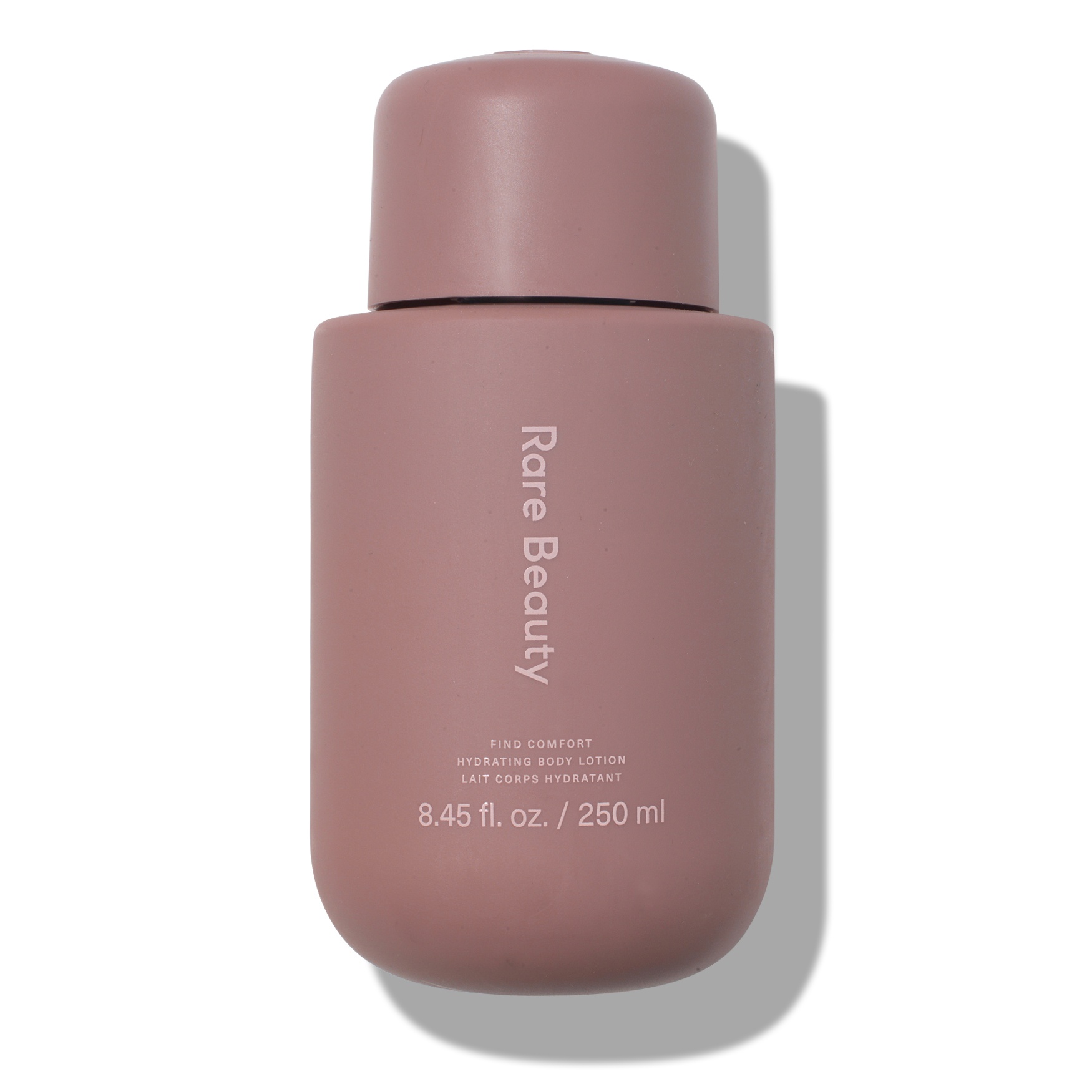 A matte mauve bottle of Rare Beauty's Find Comfort Niacinamide Hydrating Body Lotion, featuring a rounded design and simple white text, holding 8.45 fl. oz. / 250 ml.