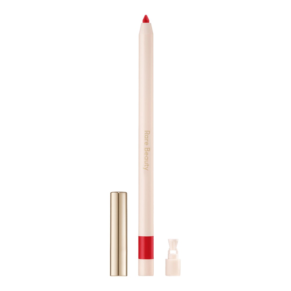 Rare Beauty Kind Words Lip Liner in Devoted features a sleek, light beige pencil with a vibrant red tip and a gold cap, emphasizing its elegant design and bold color.