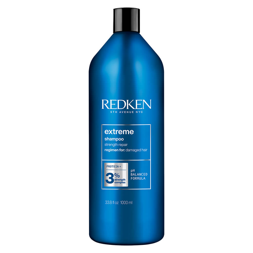 Blue plastic bottle of Redken Extreme Shampoo for damaged hair, 1000ml, featuring a sleek design, white text, and a focus on protein strength and pH balanced formula.