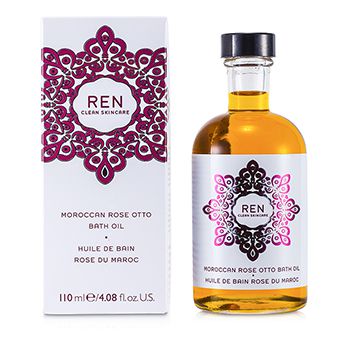 Clear glass bottle with a round shape, containing golden bath oil, labeled "REN Moroccan Rose Otto Bath Oil," with a decorative pink and white box featuring intricate patterns.
