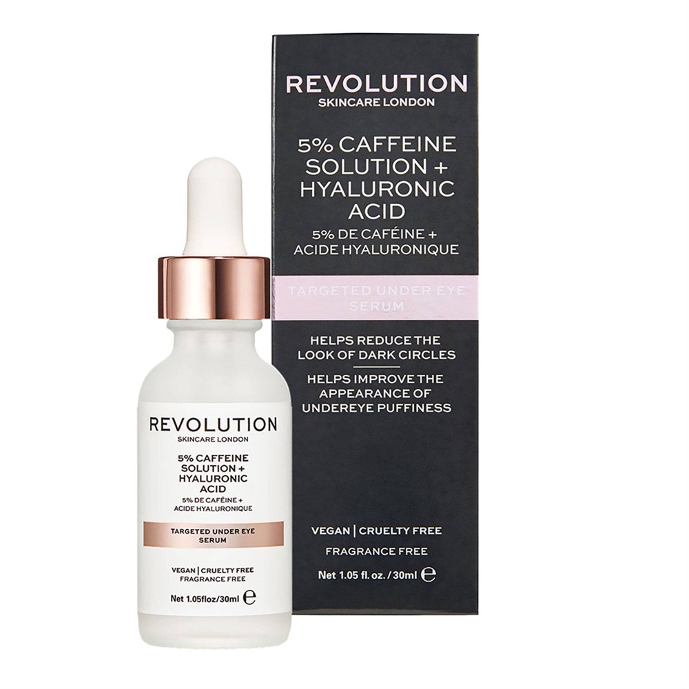 Clear glass dropper bottle with a white label, featuring "Revolution Skincare" branding, a pink dropper cap, and text highlighting 5% caffeine and hyaluronic acid for under-eye care.