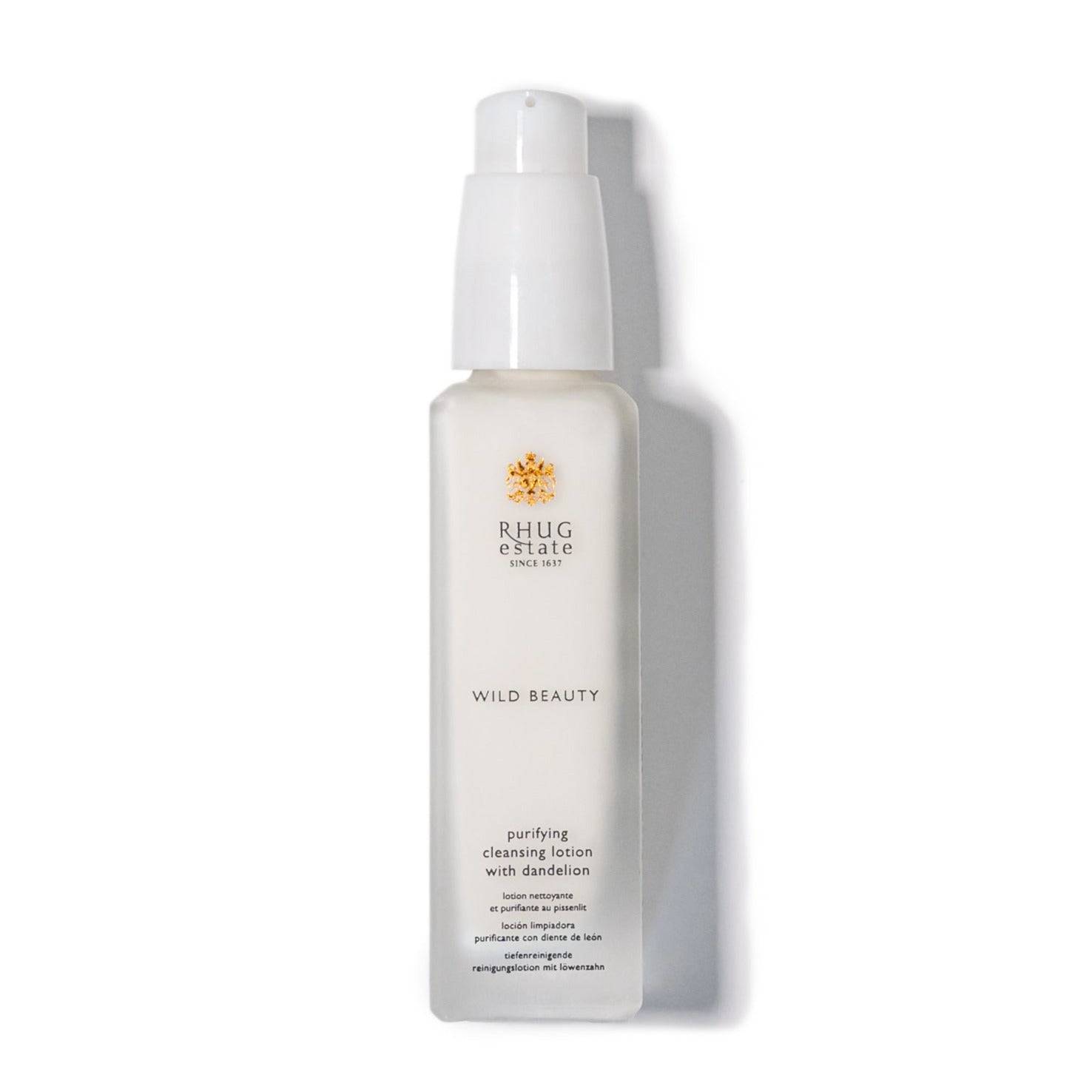 Clear plastic bottle with a white pump dispenser, labeled "Wild Beauty" and "Purifying Cleansing Lotion with Dandelion," featuring a gold logo and minimalist design.