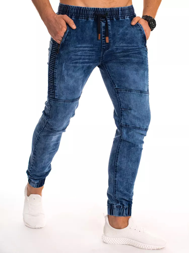 Blue denim joggers with a slim fit, featuring elastic cuffs, side pockets, and a drawstring waistband, paired with white sneakers.