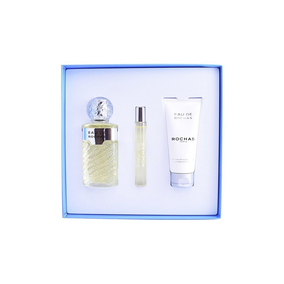 Three-piece women's perfume set by Rochas, featuring a textured glass bottle with a spherical cap, a sleek rollerball, and a white cream tube, all in a blue box.