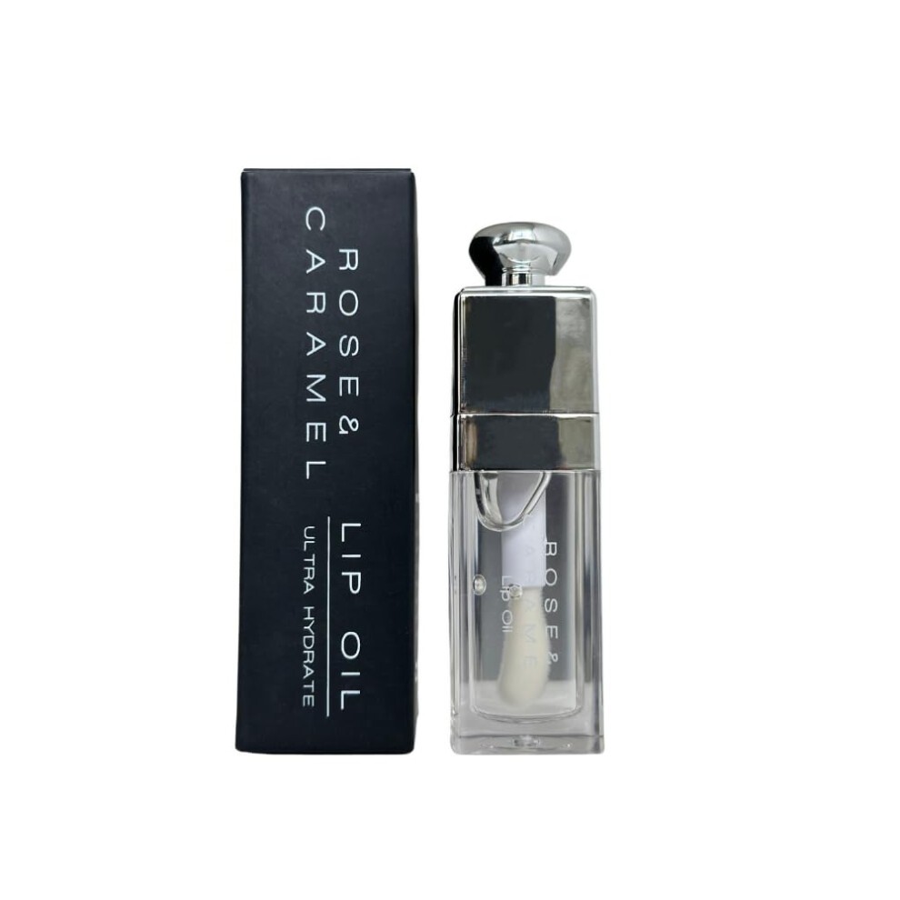 Clear lip oil in a sleek, transparent container with a silver cap, accompanied by a black and silver box labeled "Rose & Caramel Lip Oil, Ultra Hydrate."