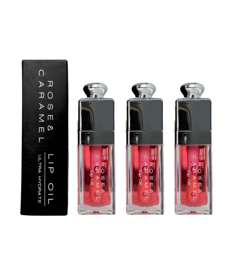 Three transparent lip oil tubes with a pink tint, featuring silver caps, alongside a sleek black box labeled "ROSE & CARAMEL LIP OIL ULTRA HYDRATE."