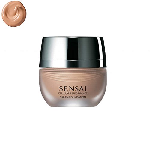 Cream foundation in a sleek, round glass jar with a silver lid, labeled "SENSAI CELLULAR PERFORMANCE" in black, alongside a swatch of almond beige cream.