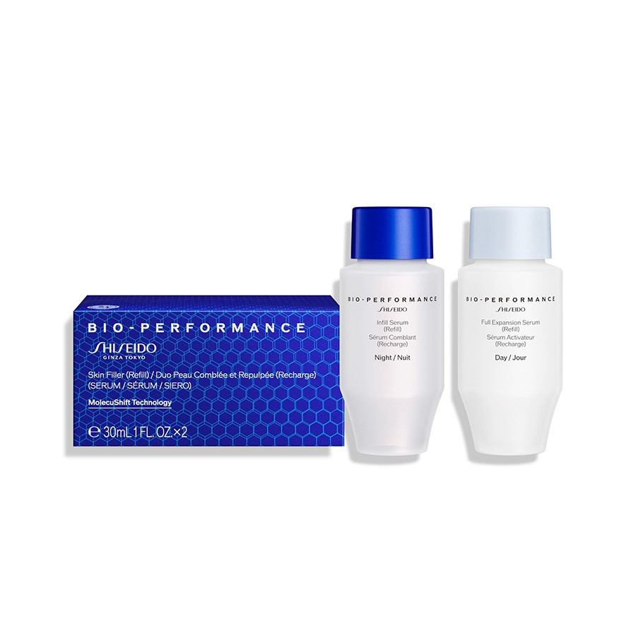 Two sleek, frosted glass serum bottles with blue and white caps, alongside a blue and purple box labeled "BIO PERFORMANCE" containing refill serums for day and night use.