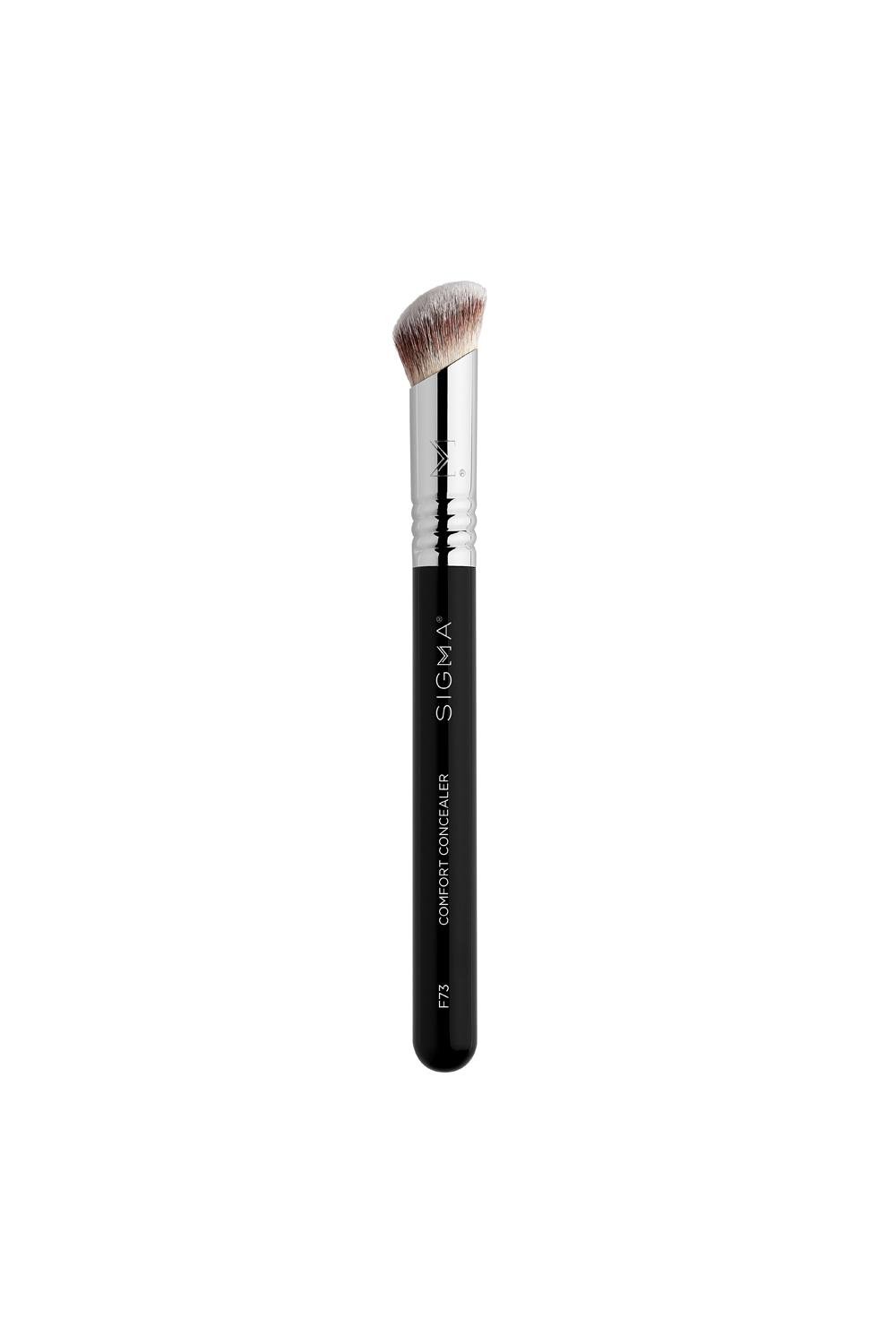 Black-handled concealer brush with a curved, soft synthetic bristle head, featuring a silver ferrule and engraved Sigma logo, designed for precise application.