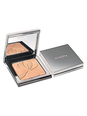 Silver compact with a mirrored lid, featuring a beige powder with an embossed floral design, labeled "sisley" in pink.