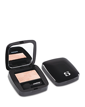 Black compact featuring a mirror and a light beige eyeshadow with a sunburst pattern, accompanied by a small applicator.