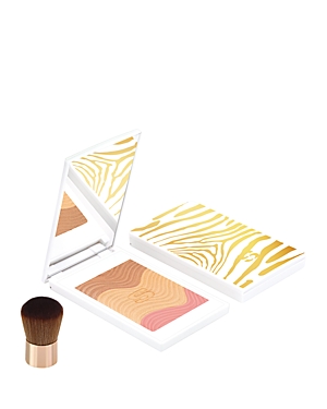 Golden peach sun glow powder compact with a mirrored lid featuring a gold zebra stripe design, accompanied by a small, soft-bristled brush.
