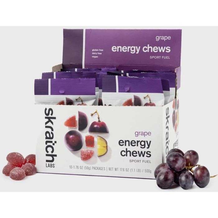 Skratch Labs Fruit Drops in grape flavor, featuring a purple box with a white base, showcasing energy chews and fresh grapes beside it. Gluten-free, dairy-free, and vegan.