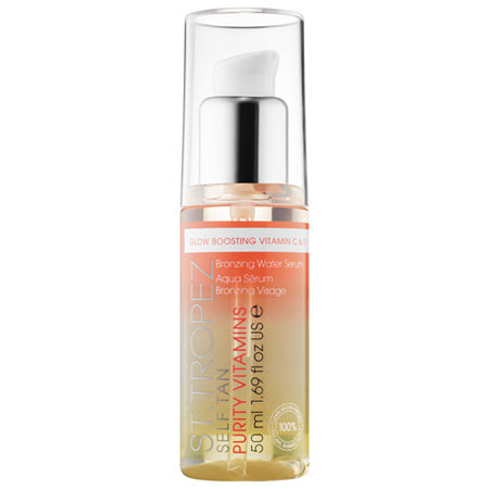 Clear glass bottle with a white pump top, containing a gradient liquid from orange to clear, labeled "St. Tropez Self Tan Purity Vitamins Face Serum 50ml."