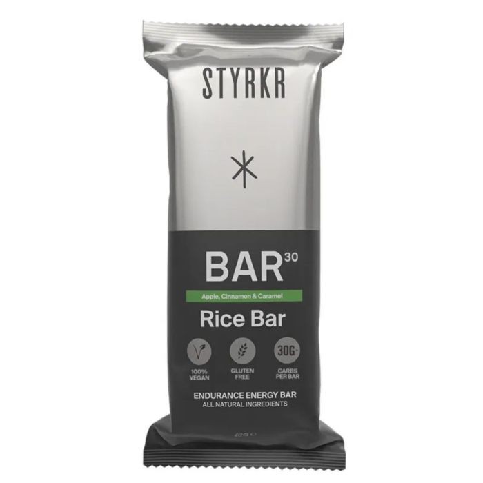 Silver and black packaging featuring "STYRKR BAR30" label, highlighting "Apple Cinnamon & Caramel" flavor, with details on being vegan, gluten-free, and containing 30g of carbs.