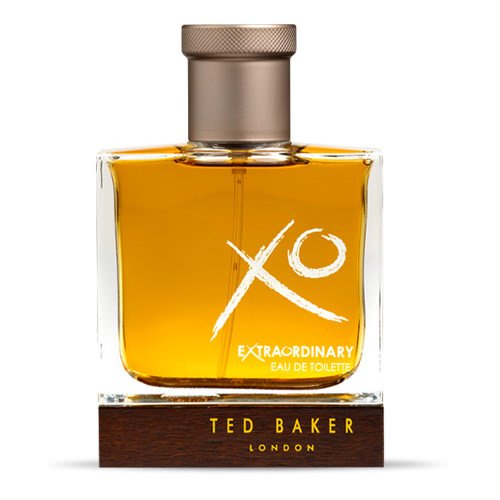 Clear glass bottle with a square base, featuring a gold and brown cap, filled with amber-colored fragrance, labeled "XO Extraordinary" and "Ted Baker London" on a wooden stand.