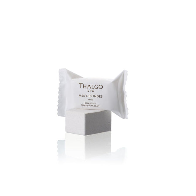Thalgo Mer Des Indes Precious Milk Bath Set featuring six individually wrapped white sachets, each labeled with "Thalgo Spa," placed on a light gray pedestal.