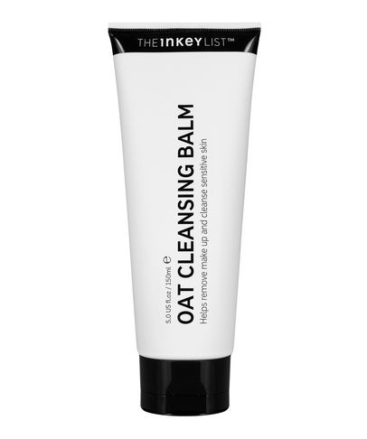 White tube with a black cap, labeled "OAT CLEANSING BALM" in bold text, featuring a minimalist design and claims to help remove makeup and soothe sensitive skin.
