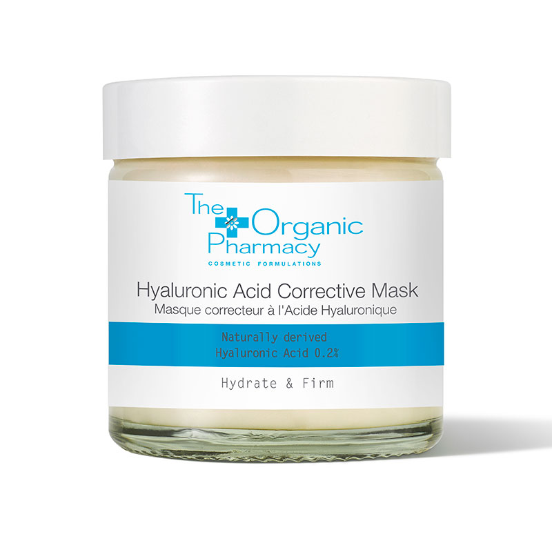 White glass jar with a silver lid, labeled "The Organic Pharmacy Hyaluronic Acid Corrective Mask," featuring blue accents and text highlighting hydration and firming properties.