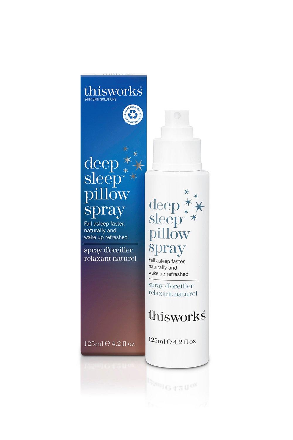 White spray bottle with a pump top, labeled "Deep Sleep Pillow Spray" in blue text, alongside a colorful box featuring stars and the brand name "This Works."