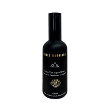 Black spray bottle with a matte finish, featuring gold text that reads "Three Warriors Face Tan Aqua Mist," with a black cap, holding 100ml of product.
