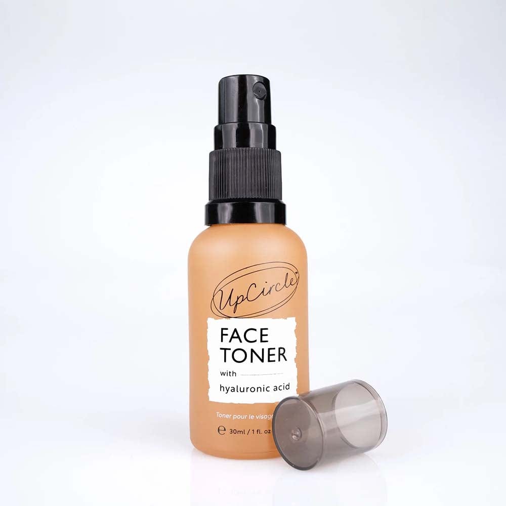 Clear 30ml spray bottle of UpCircle Face Toner with Hyaluronic Acid, featuring a black pump top and a light amber liquid, accompanied by a removable cap.