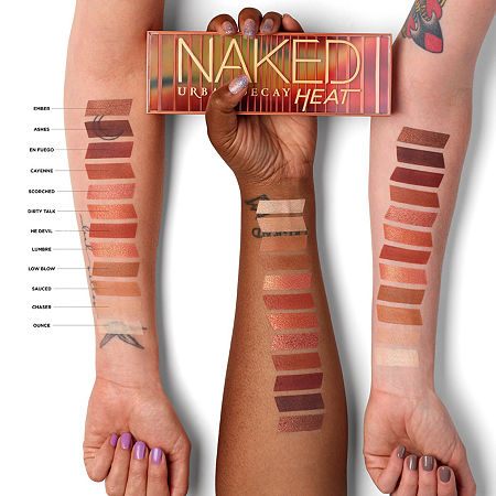 Urban Decay Heat Naked Eye Shadow Palette displayed with swatches on two arms, showcasing warm, earthy tones ranging from deep browns to shimmery coppers in a sleek, rectangular case.