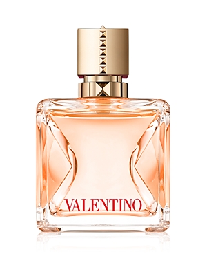 Clear glass bottle with a geometric design, featuring a gold cap adorned with pyramid studs, and a peach-colored liquid inside, labeled "VALENTINO" in bold red letters.