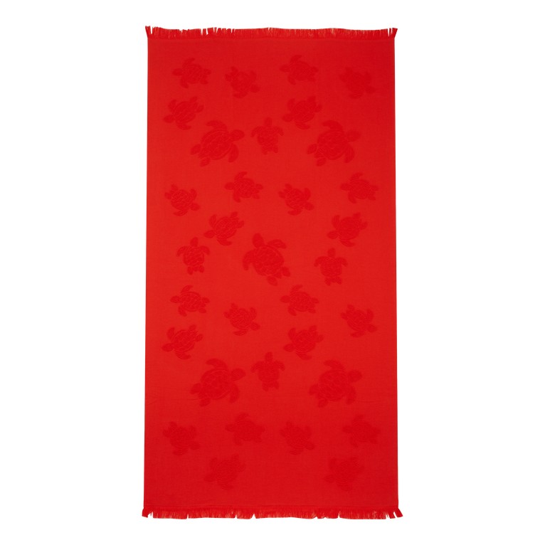 Bright red organic cotton beach towel featuring a jacquard pattern of turtles, with fringed edges and a generous one-size-fits-all design.