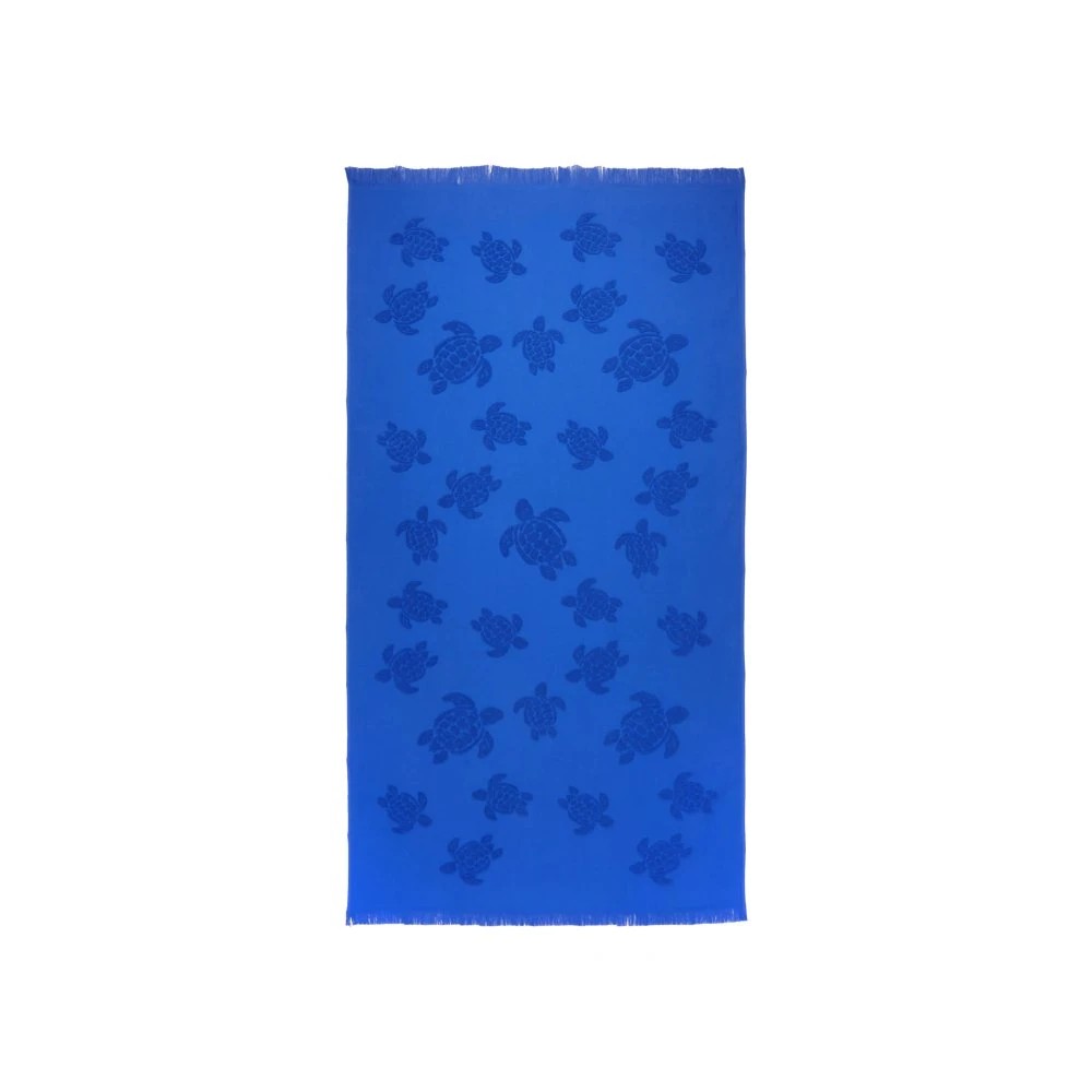 Bright blue organic cotton beach towel featuring a jacquard design of turtles, with fringed edges and an overall vibrant, playful aesthetic.