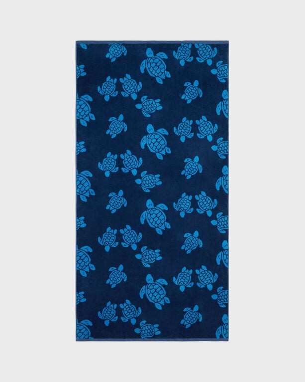 Organic cotton beach towel in sand and blue, featuring a jacquard design of turtles, with a soft texture and oversized dimensions for versatile use.