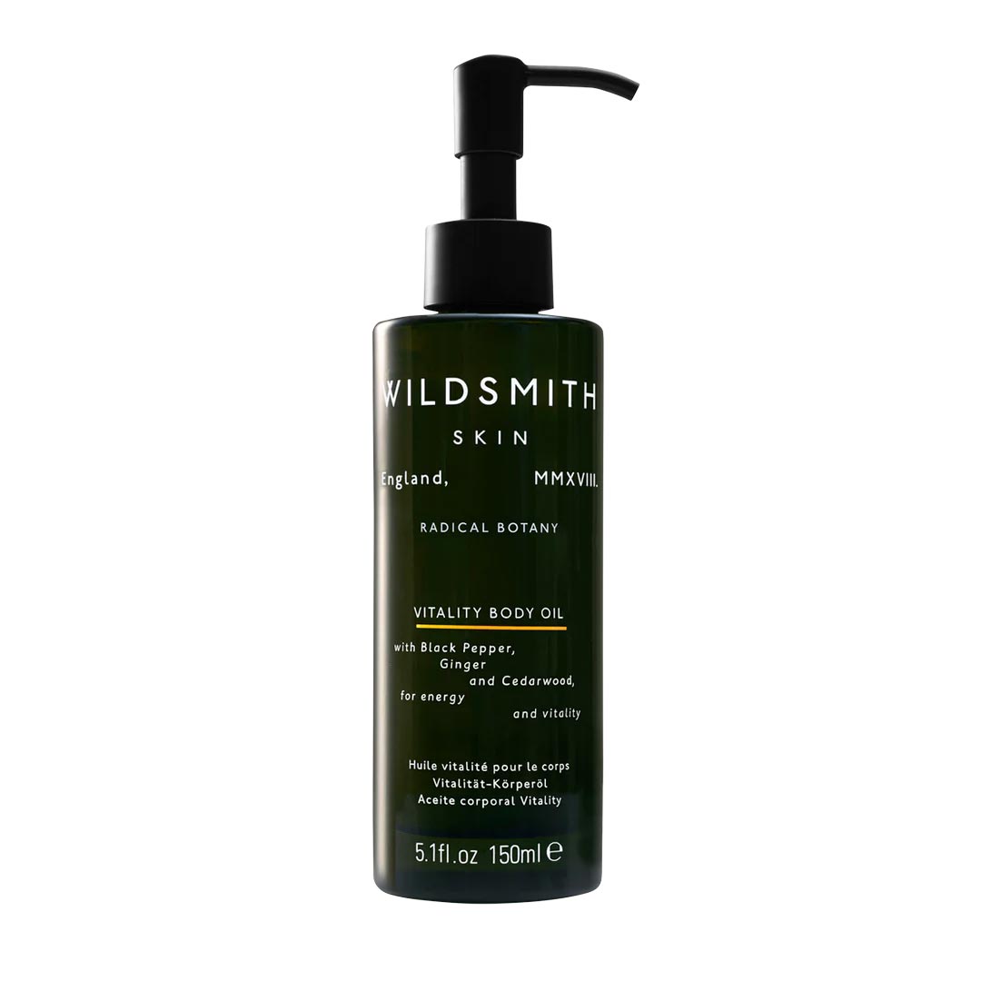 Dark green glass bottle with a black pump, labeled "WILDSMITH SKIN VITALITY BODY OIL 150ml," featuring ingredients like black pepper, ginger, and cedarwood for nourishment and energy.