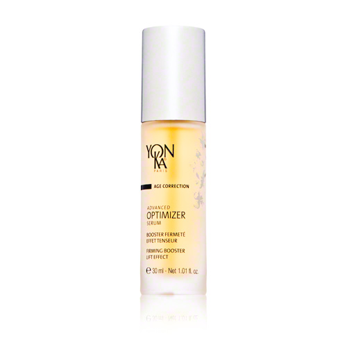 Clear glass serum bottle with a white pump top, labeled "Yon-Ka Age Correction Advanced Optimizer Serum," featuring a yellow liquid inside and elegant branding.