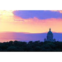 Sunset view of Lancaster House Hotel with distant hills, silhouetted trees, and a domed building under a colorful sky.
