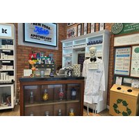 Kiehl's beauty counter with skincare products, skeleton in lab coat, and promotional signage in a brick-walled store.
