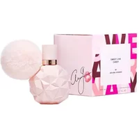 Pink geometric perfume bottle with fluffy pom-pom, next to a pink and white box labeled "Sweet Like Candy" by Ariana Grande.