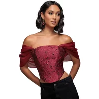 Red Goddiva bustier with organza wings, off-shoulder design, intricate lace details, paired with black pants.
