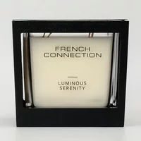 French Connection candle in black square holder with "Luminous Serenity" label, white wax, and wooden wicks.