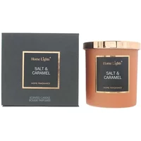 Salt Caramel candle in a brown glass jar with a gold lid, next to a black box with gold accents.