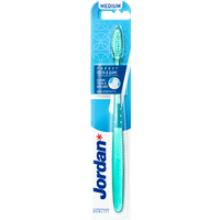 Teal Jordan toothbrush with medium bristles, ergonomic handle, and blue packaging labeled "Teeth & Gums Medium."